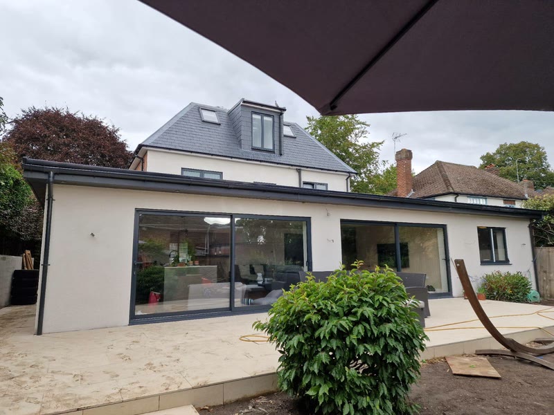 Finished rear elevation of the orangery extension — four aluminium-framed sliding glass panels onto the patio with the original semi above